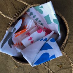 Five different coloured linen union tea towels in a basket